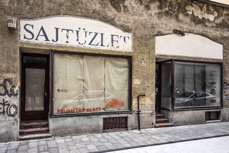 Hungary, Budapest: Street scene with run down house front facade, closed cheese shop (Sajtuzlet) and blinded shop windows in city center of the Hungarian capital - concept business. Feb 05, 2019のeditorial素材