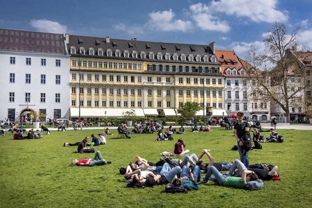 Germany, Bavaria, Munich: People tourists residents men women relax on Marienhof square in the city center of the Bavarian capital with building of Dallmayr company in the background. April 22, 2016のeditorial素材