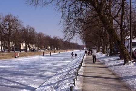 Germany, Bavaria, Munich: People men women residents and white frozen canal water in cold snowy winter time near Nymphenburg Palace - concept winter activities leisure lifestyle. February 28, 2018のeditorial素材