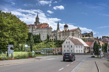 Germany, Sigmaringen, upper Danube: Street scene with panoramic view of famous ancient Hohenzollern castle which overlooks the old German city town with blue sky in the background. July 31, 2017のeditorial素材