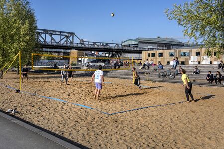 Germany, Berlin, Kreuzberg, Park am Gleisdreieck: Young sportspeople men women play volleyball in the city center of the German capital with metro subway station viaduct and blue sky. May 01, 2019のeditorial素材