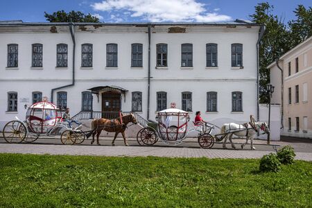 Russia, Vladimir Oblast, Golden Ring, Suzdal: Two traditional horse drawn carriages opposite the famous Torgovaya Square in the center of one of the oldest Russian towns with blue sky. Jul 02, 2019のeditorial素材