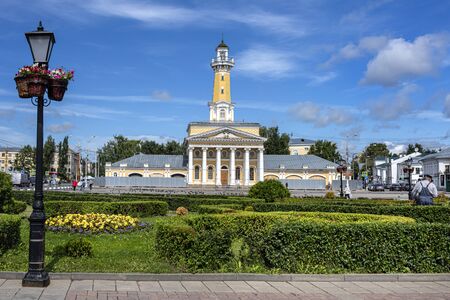 Russia, Golden Ring, Kostroma: Famous fire observation watchtower at Susaninskaya Square in the city center of the Russian town with lamp post, green public park, flowers, blue sky. Jul 05, 2019のeditorial素材
