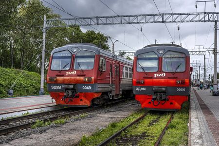 Russia, Karelia, Petrozavodsk: Front view of two red electric trains locomotives of Russian state-owned Russian Railways (OAO RZhD) at Central Train Station with people and and platform. Jul 11, 2019のeditorial素材
