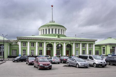 Russia, Barents Sea, Murmansk: Front view of Central Railway Station main building and entrance in the city center of the Russian town with people, cars and grey sky - travel destination. Jul 14, 2019のeditorial素材