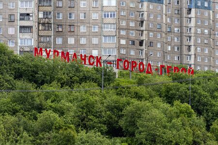 Russia, Murmansk: Red city sign (Murmansk - Gorod Geroy or Hero City) overlooking the city center of the northern Russian town with green trees and typical apartment buildings - travel. Jul 15, 2019のeditorial素材