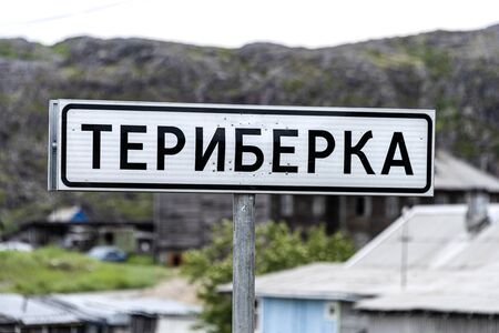 Russia, Arctic, Kola Peninsula, Barents Sea, Teriberka: City limit sign of the old Russian settlement small fishing village on grey rainy day with run down houses building skyline cityscape - close upのeditorial素材