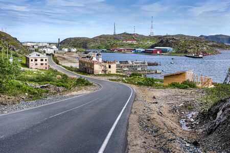 Russia, Arctic, Kola Peninsula, Barents Sea, Teriberka: Road down to the fishing harbor of Lodeiny, the newer part of old Russian settlement small fishing village with hilly coastline. Jul 19, 2019のeditorial素材