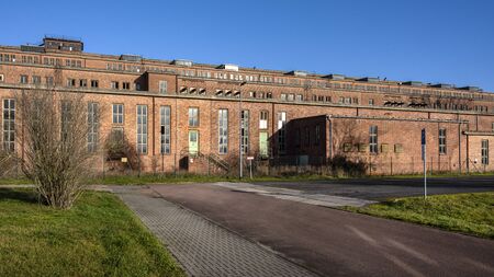 Germany, Saxony-Anhalt, Vockerode: Street view of big old defunct shut down former Vockerode lignite power plant building with brick stone facade, no chimneys and blue sky - concept energy lost placeの写真素材