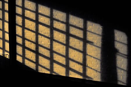 Dark shadow on a stonework wall illuminated by golden sunlight - concept dramatic contrast film noir...