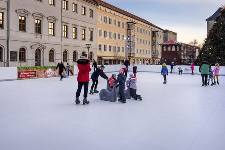 Germany, Saxony-Anhalt, Dessau-Rosslau: Colorful dressed people men women children while ice skating in the city center of the famous German town at winter time - concept fun activity. Dec 29, 2019のeditorial素材