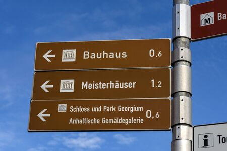 Germany, Saxony-Anhalt, Dessau-Rosslau: Direction sign post to famous Bauhaus building, Meisterhauser and Dessau Palace castle in the city center of the German town with blue sky. Dec 30, 2019のeditorial素材