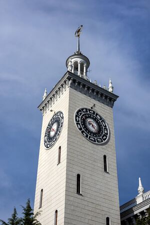 Russia, Black Sea, Sochi: Central railway station main building (Vokzal) in the city center of the Russian town with high clock tower, blue sky in background - public transport travel. Jun 27, 2019のeditorial素材