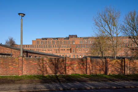 Germany, Saxony-Anhalt, Vockerode: Street view of big old defunct shut down former Vockerode lignite power plant building with brick stone facade, no chimneys and blue sky - concept energy lost placeのeditorial素材