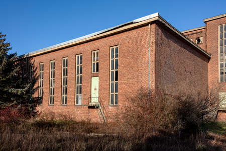Germany, Saxony-Anhalt, Vockerode: Street view of big old defunct shut down former Vockerode lignite power plant building with brick stone facade, no chimneys and blue sky - concept energy lost placeのeditorial素材
