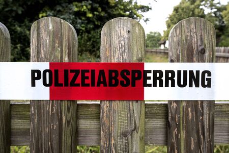 Germany: Red white police cordon (Polizeiabsperrung) on a wooden fence.