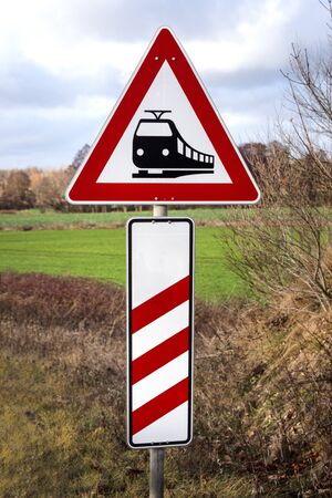 Germany, German traffic sign: Caution! Railroad crossing without gates with red white triangle, black train pictogram and three-lined bake - concept traffic train transport risk sign symbol danger