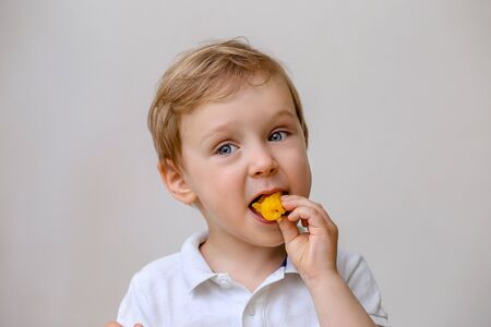 a light boy todler eats an orange fruit.の写真素材