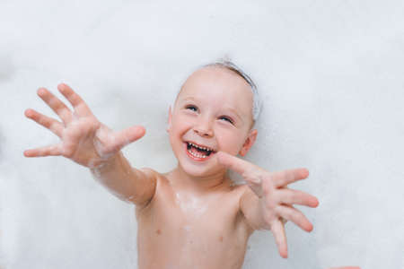 The baby boy lies foam laughing and pulls his hands into the camera.の写真素材