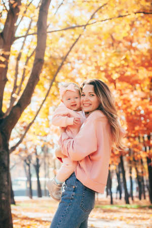 A womans mother holds a baby girl in her arms on a walk in an autumn park.の写真素材