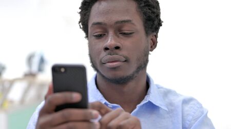 Close-up shot of African Man scrolling onPhoneの写真素材