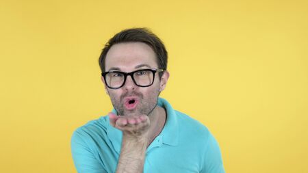 Flying Kiss by Casual Man Isolated on Yellow Backgroundの写真素材
