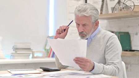 Senior Old Man Reading Documents at Workの写真素材