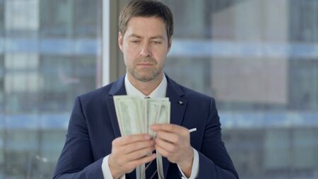 Middle Aged Businessman Counting the Money at Workの写真素材