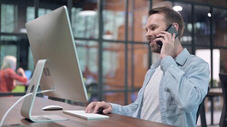 Young Man Talking on Phone at Work