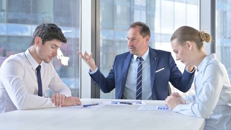 Middle Aged Businessman having getting Angry at Assistants on Office Tableの写真素材