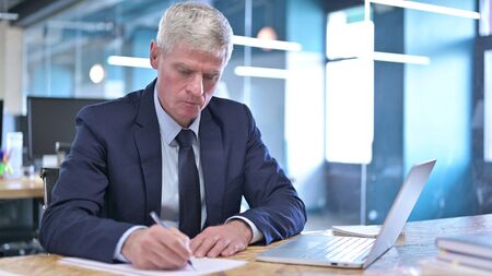 Middle Aged Businessman Writing on Papersの写真素材