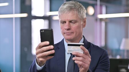 Portrait of Middle Aged Businessman using Credit Card on Smartphone, Online Shoppingの写真素材