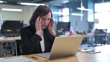 Tired Old Businesswoman with Headache at Workの写真素材