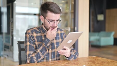 Sad Young Designer having Loss on Tablet in Officeの写真素材