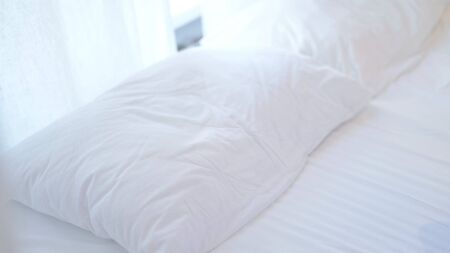 Empty Bed with white Pillow and Bedsheetの写真素材