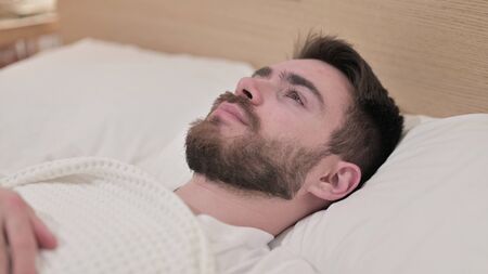 Worried Young Man Trying to Sleep in Bed