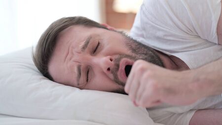 Close up of Attractive Sick Beard Young Man Coughing in Bedの写真素材