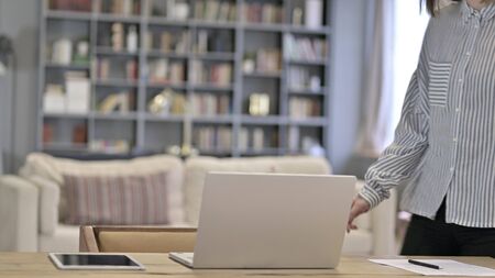 Young Woman Coming and Sitting in Loft Officeの写真素材