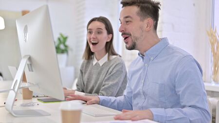 Creative Team Celebrating Success on Desktop in Modern Office