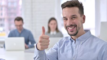 Thumbs Up by Creative Young Man in Modern Officeの写真素材
