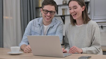 Online Video Chat on Laptop at Home by Cheerful Young Couple