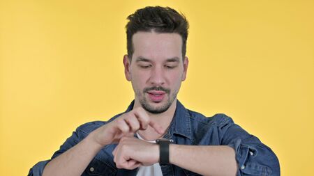 Portrait of Professional Young Man using Smartwatch, Yellow Background