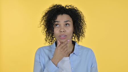 Attractive African Woman Thinking and getting Idea, Yellow Backgroundの写真素材