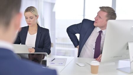 Tired Businessman having Back Pain in Modern Office
