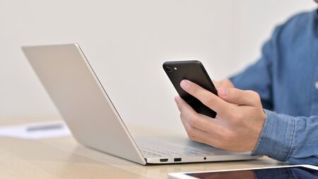 Close up of Man using Smartphone with Laptopの写真素材
