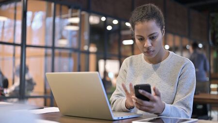 African Woman Using Smartphone and Laptopの写真素材