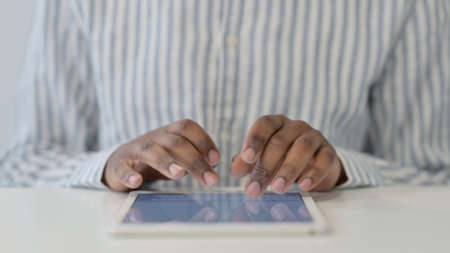 Close Up of African Hands Typing on Tablet on Desk