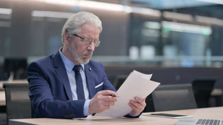 Old Businessman Reading Documents in Office