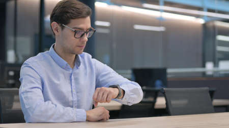 Young Man Feeling Curious while using Smart Watch