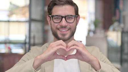 Portrait of Young Man showing Heart Sign by Handの写真素材